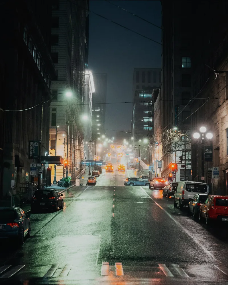 The rainy city street after a muted Eterna cinematic treatment with softer orange lights, cool buildings, and restrained highlights.